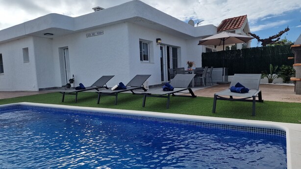A pool area with lounge chairs and a sign reading "CASA DEL PERRO".