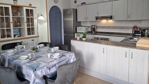 Moderni keittiö, jossa on valkoiset kaapit, sisäänrakennettu mikroaaltouuni ja ruostumattomasta teräksestä valmistettu jääkaappi.