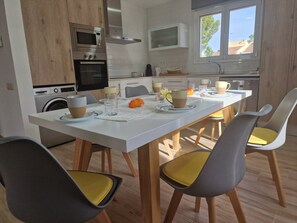 Eine moderne Küche mit Einbaugeräten, ein Essbereich mit Stühlen und einem Tisch sowie ein Fenster mit Blick.