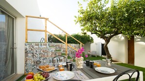 An outdoor dining area with a table set for breakfast, including fruits, pastries, and beverages. - Villa Loria - Luxurious Villa with private pool located in the city centre (San Vito Lo Capo)