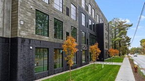 A modern building with a black and grey facade, numbered 1825, and a well-maintained lawn with young trees. - Stay, play, relax- Sleeps 4, close to downtown with rooftop hot tubs! (Traverse City)