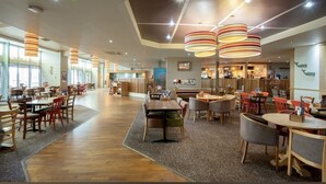 Un restaurant espaiós amb diverses sales de dinar, taules i cadires de fusta, i lluminàries pendents modernes.