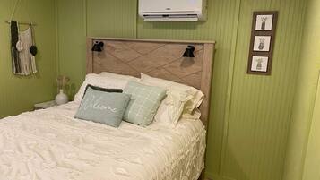 Un dormitorio con cama, aire acondicionado de pared y un tapiz de macramé.