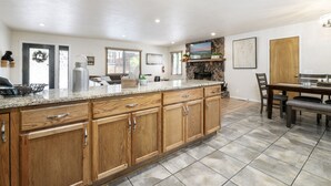 A spacious kitchen with wooden cabinets, granite countertops, and a dining area with a bench.