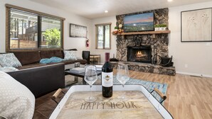A cozy living room with a stone fireplace, a sofa, and a tray with a bottle of wine and glasses.