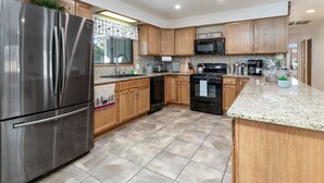 A modern kitchen with stainless steel appliances, wooden cabinets, and a granite countertop.