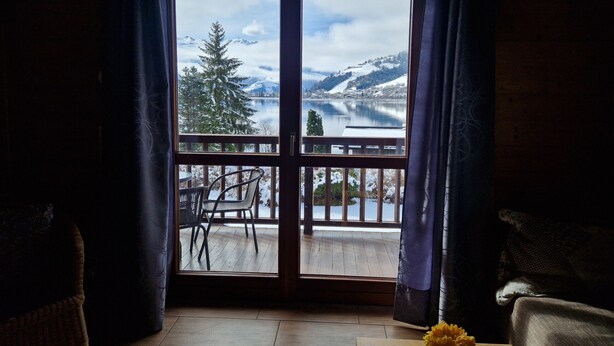 A room with a view of a lake and mountains through a large window. - Lake and Mountain View (Zell am See)
