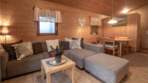A cozy cabin interior with a wooden ceiling, a sofa, a dining table, and a small table with a plant. - Lake and Mountain View (Zell am See)