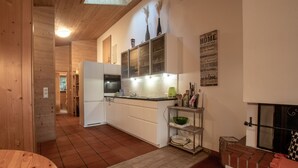 A kitchen with wooden cabinets, a refrigerator, a sink, and a brick fireplace. - Lake and Mountain View (Zell am See)