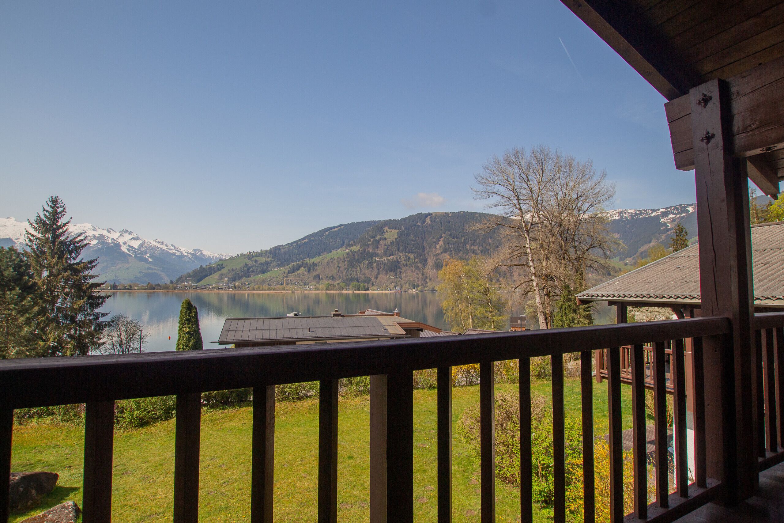 A lakeside view from a wooden deck with a mountain backdrop.