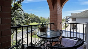A balcony with wicker chairs, a glass table, and a potted plant. - On the Esplanade (Cairns North)