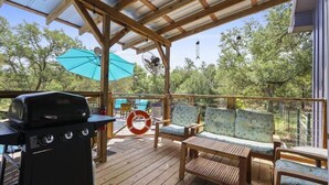 A covered outdoor deck with a grill, seating area, and a lifebuoy.