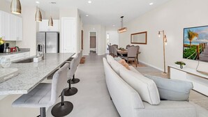 A modern kitchen with a central island, bar stools, and pendant lighting.