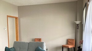 A living room with a grey sofa, a wooden chair, a patterned rug, and a tall floor lamp.