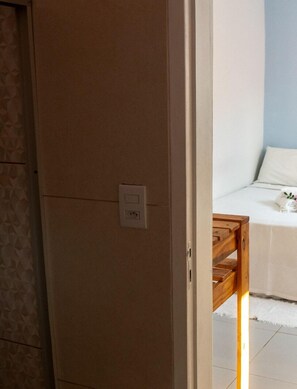 A room with a bed, a wooden side table, and a wall socket. - Pousada Vento Terral (Tibau do Sul)