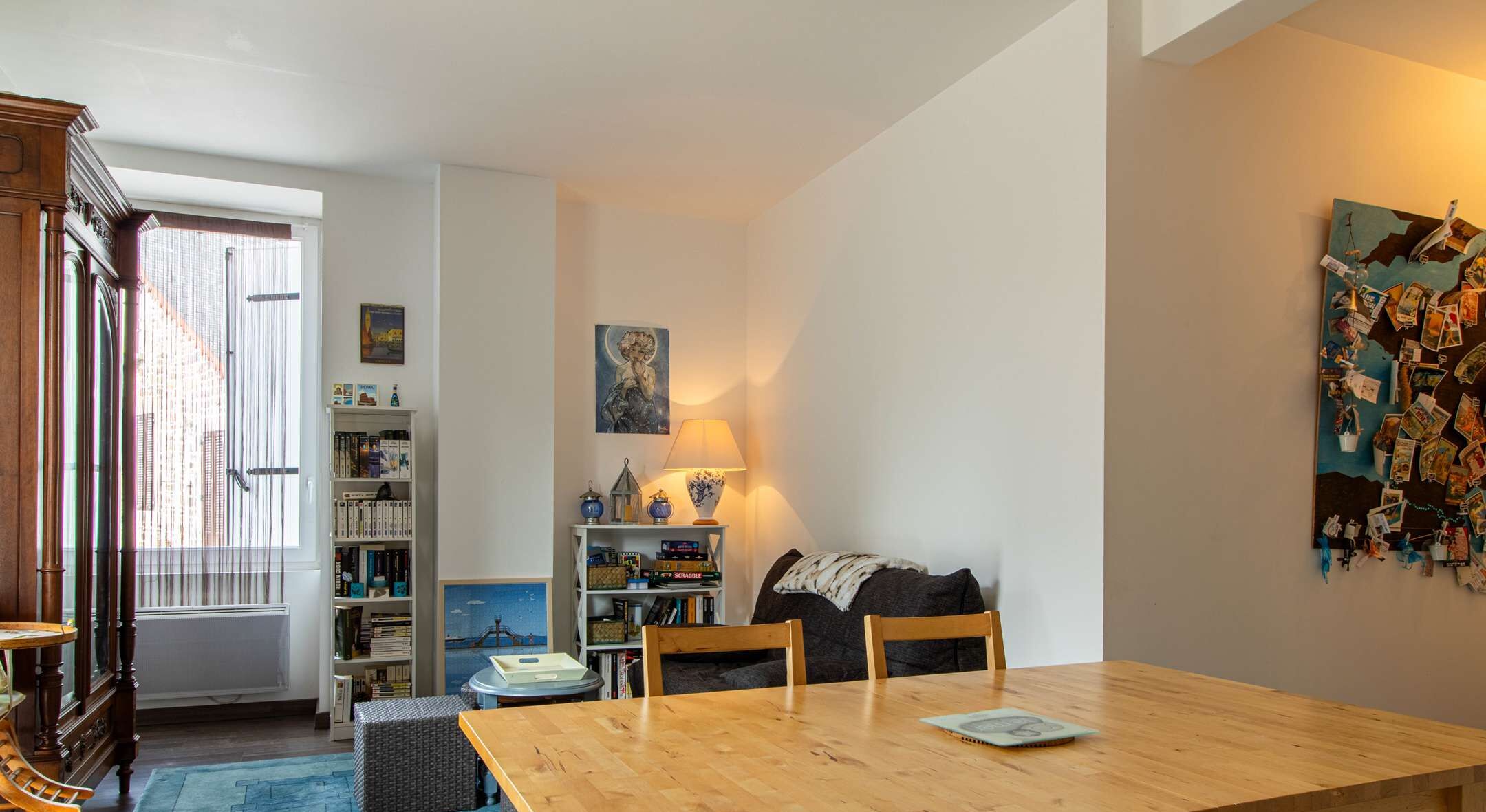 Een gezellige woonkamer met een houten tafel, een bank en een boekenkast vol boeken.