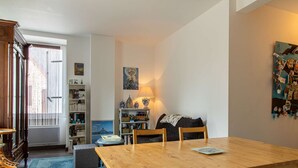 A cozy living room with a wooden table, a sofa, and a bookshelf filled with books. - Apartment near beaches in Fréhel | 4 guests | Ref 359 (FREHEL)