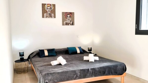 A bedroom with a bed, pillows, a lamp, and artwork on the wall.