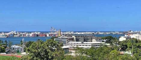 Un paysage urbain côtier avec des bâtiments modernes, une marina et un ciel bleu dégagé.