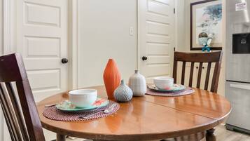 A dining table with four chairs, a white door, and a kitchen area with a refrigerator.