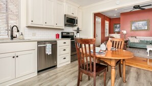Une cuisine moderne avec des meubles blancs, des appareils en acier inoxydable et un coin repas comprenant une table et des chaises en bois.