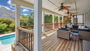 Une terrasse extérieure couverte avec une piscine, des rampes en bois et du mobilier d’extérieur.