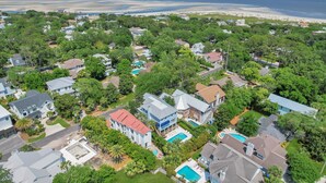 Une vue aérienne d’un quartier résidentiel avec des maisons, des arbres et une plage en arrière-plan.