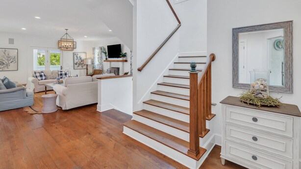 Un vaste espace de vie comprenant un escalier, des meubles blancs et un téléviseur.