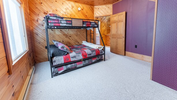 A bunk bed in a room with wooden walls and a purple accent wall.