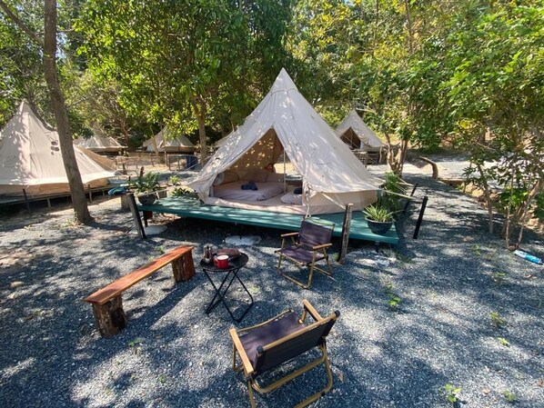Un camping con varias tiendas de campaña, una mesa de picnic verde y sillas de camping.