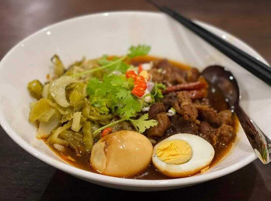 A bowl of soup with meat, vegetables, and a boiled egg.