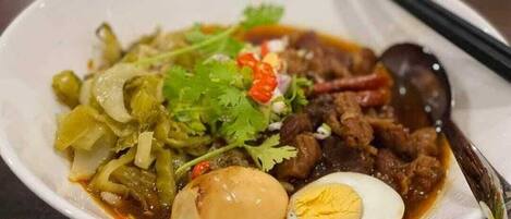 A bowl of soup with meat, vegetables, and a boiled egg.