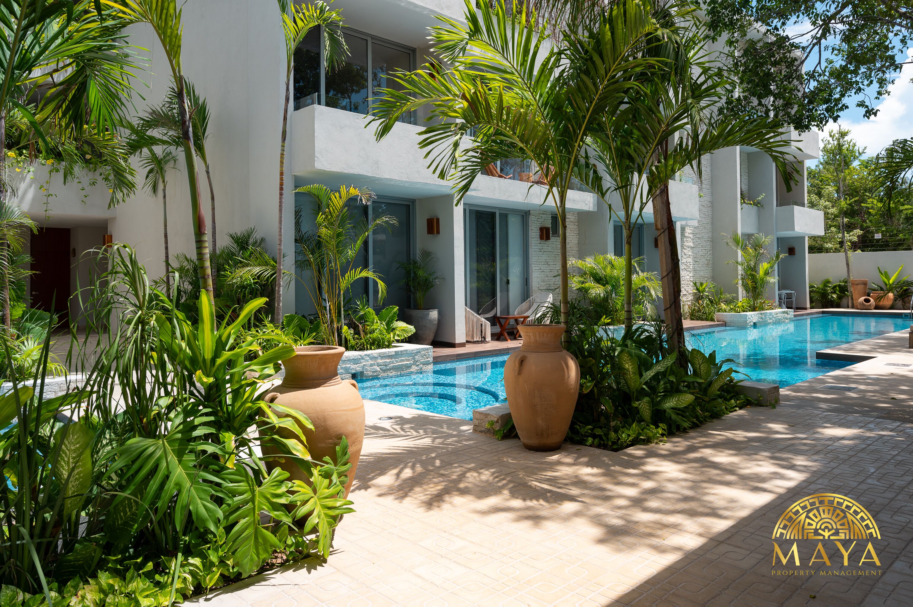 Un bâtiment moderne doté d’une piscine entourée de plantes tropicales.