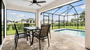 Un patio techado con piscina, mobiliario exterior y vistas al vecindario.