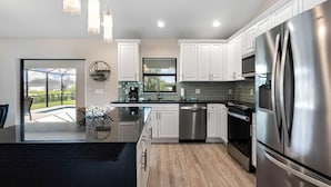 Una cocina moderna con armarios blancos, electrodomésticos de acero inoxidable y una isla grande.