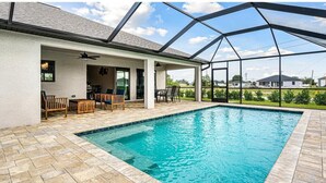 Una piscina techada al aire libre con un patio, mobiliario y vistas del paisaje circundante.