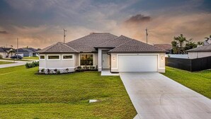 Una casa moderna de un piso con garaje, césped cuidado y entrada para vehículos.