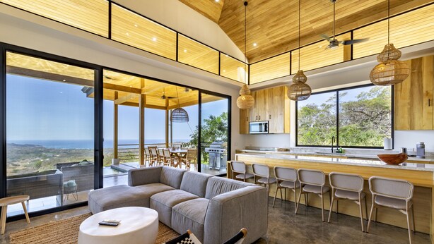 A modern kitchen with a large island, bar seating, and a view of the outdoors. - La Joya De La Selva ~ An Eco-Luxury Experience (Nosara)