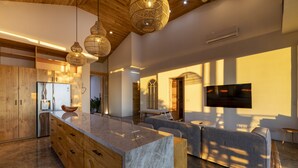 A modern kitchen with wooden cabinets, a marble island, and pendant lighting. - La Joya De La Selva ~ An Eco-Luxury Experience (Nosara)