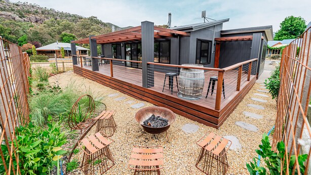 Une terrasse extérieure moderne, dotée d’un foyer, de sièges et offrant une vue sur un paysage montagneux.