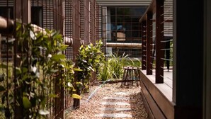 Un chemin menant à un bâtiment à l’architecture moderne, agrémenté d’une clôture en bois et de verdure d’un côté.