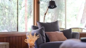 A room with a dark-colored sofa, a vase with dried flowers, and a tall floor lamp.
