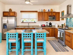 Una cocina con una isla central, armarios de madera, un refrigerador de acero inoxidable y un microondas.