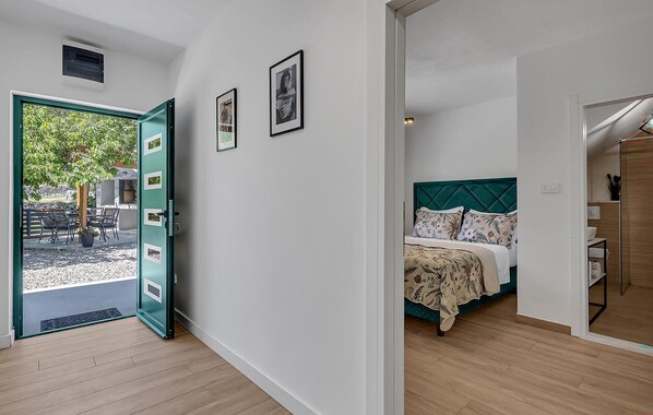 A room with a bed, a door leading to an outdoor area, and a wall with framed pictures. - Pet friendly home in Rascane (Rascane)