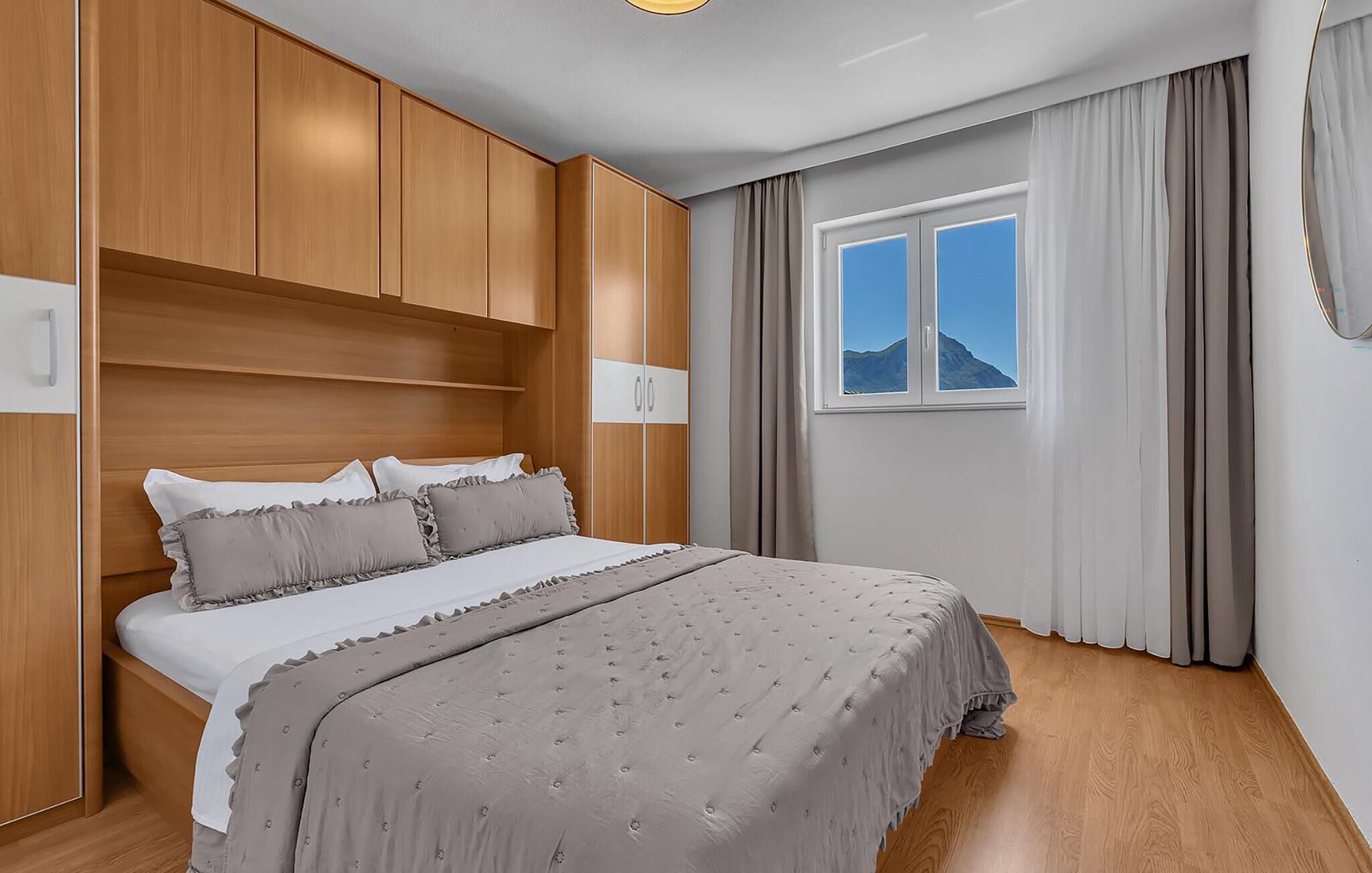 Un dormitorio con cama, armario de madera y ventana con vista a la montaña.