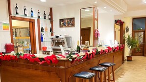 A bar area with a wooden counter, bar stools, a coffee machine, and various bottles. - Hotel Vico Alto Siena (Siena)