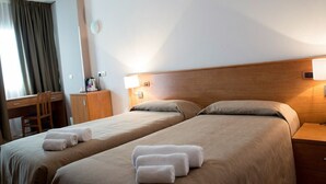 A hotel room with two beds, a desk, a chair, and a nightstand with a lamp. - Hotel Vico Alto Siena (Siena)