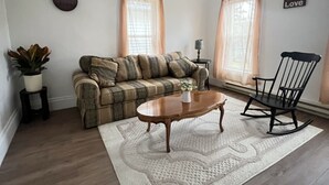 A living room with a sofa, a coffee table, a rocking chair, a ceiling fan, and a rug. - Spacious 2 bedroom apartment  (Warren)
