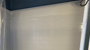 A bathroom with white subway tiles, a bathtub, and a shower curtain. - Spacious 2 bedroom apartment  (Warren)
