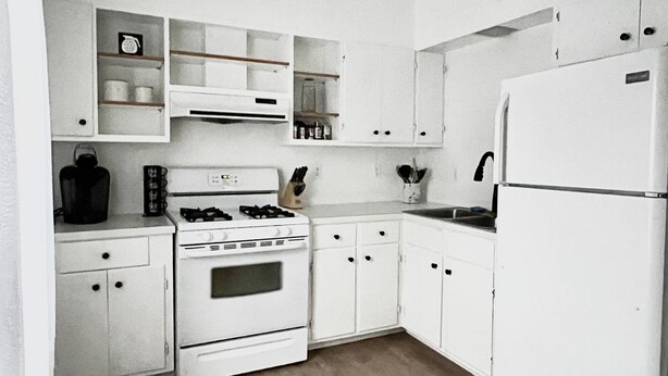 A compact kitchen with white cabinetry, a stove, a sink, and a refrigerator. - Spacious 2 bedroom apartment  (Warren)